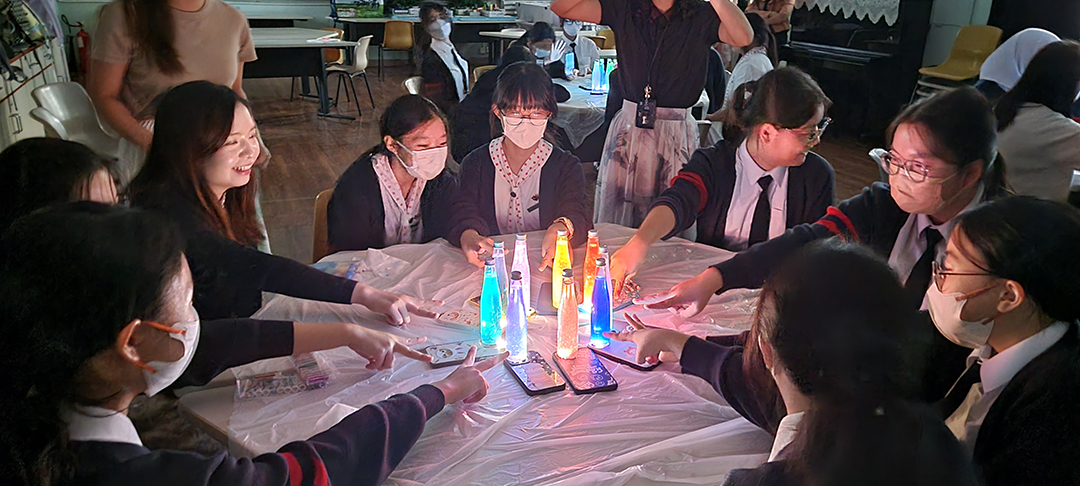 A group of people wearing masks and standing around a tableDescription automatically generated