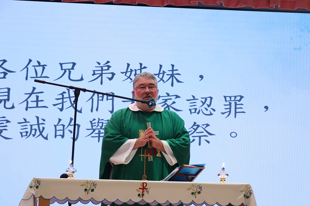 A person standing in front of a bannerDescription automatically generated