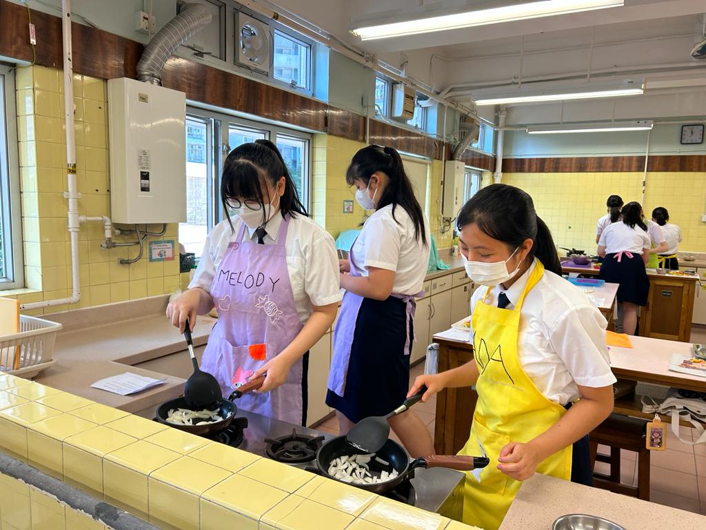 A group of women wearing masks cooking in a kitchenDescription automatically generated