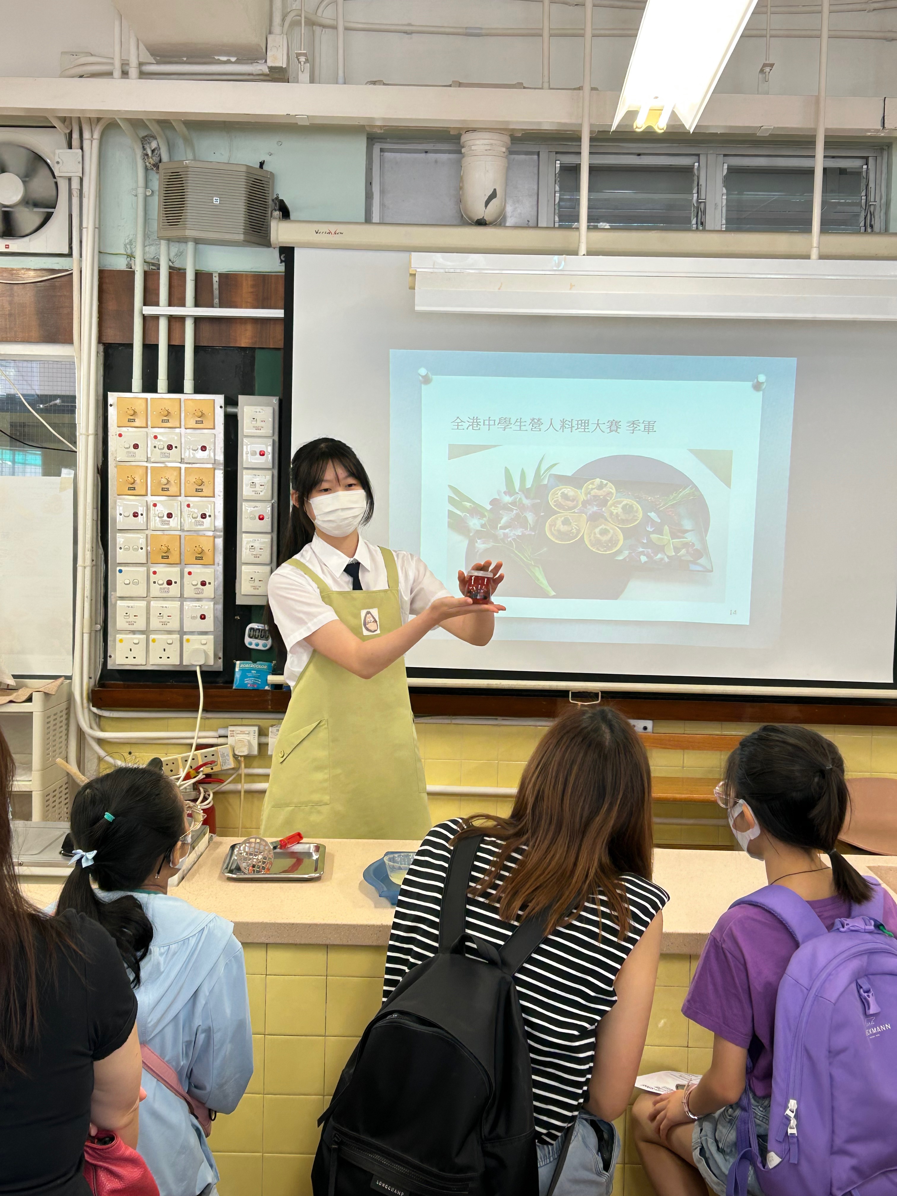 A person wearing a mask and standing in front of a white boardDescription automatically generated