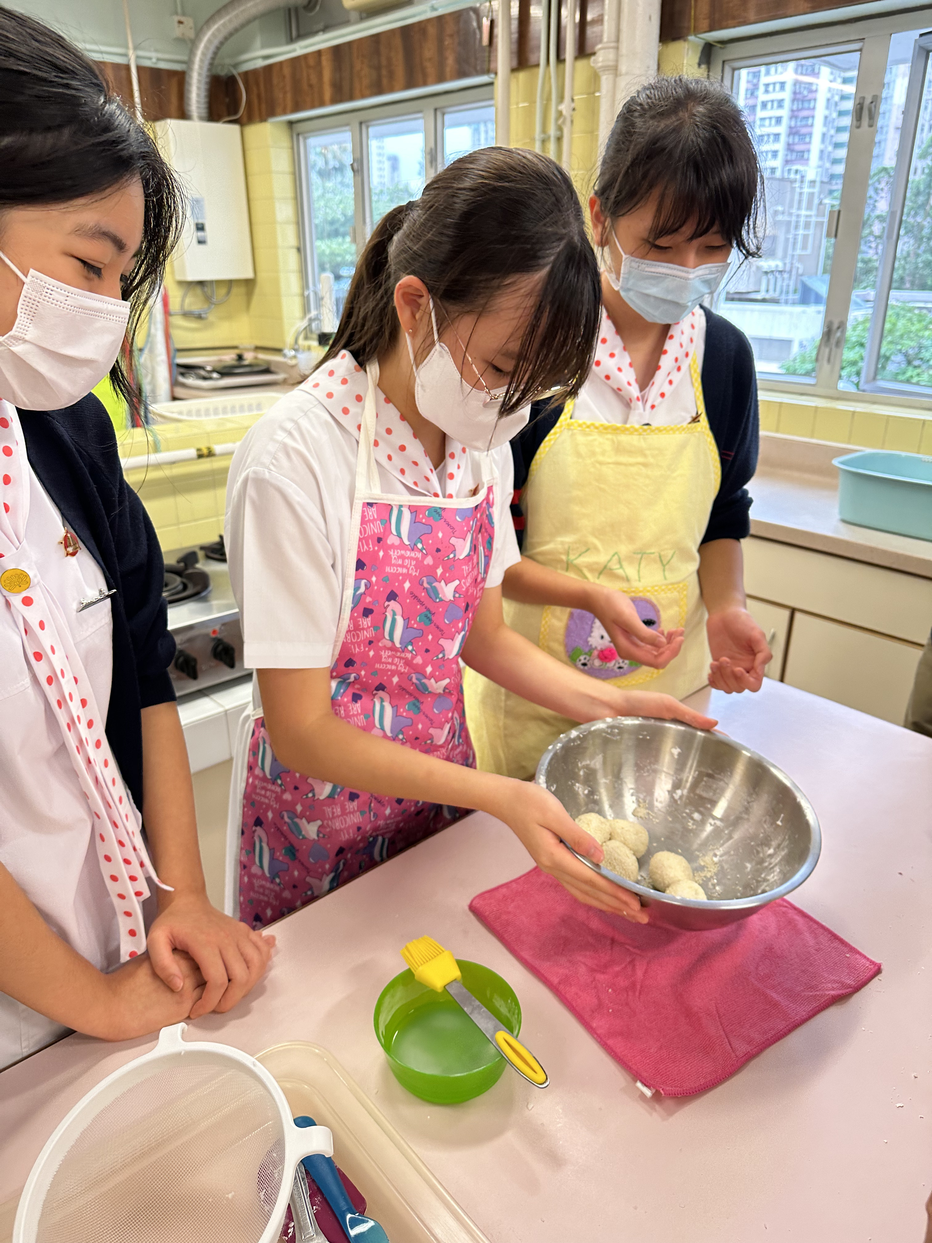 A group of girls wearing masks and cookingDescription automatically generated