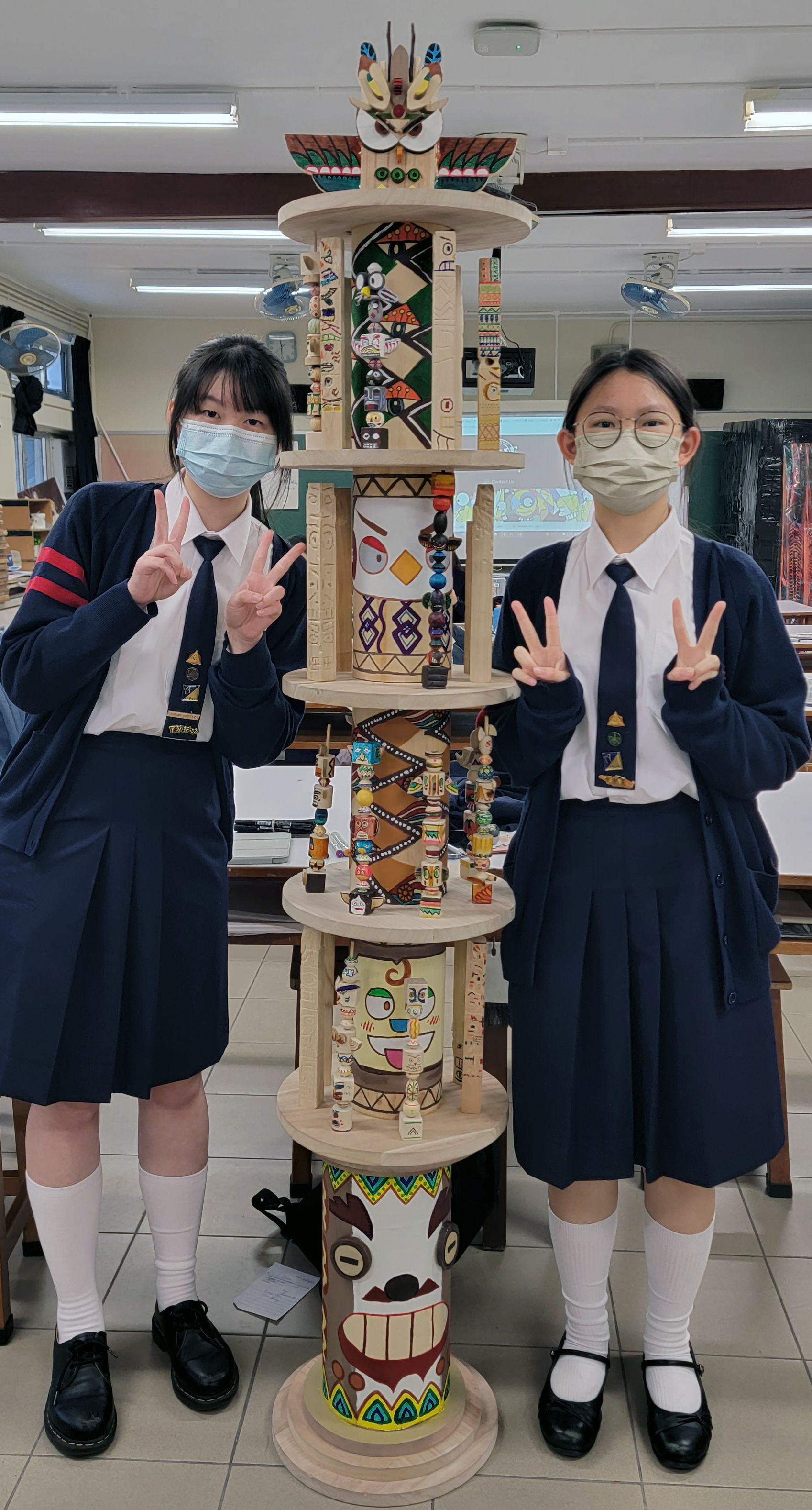 Two girls wearing face masks posing with a displayDescription automatically generated